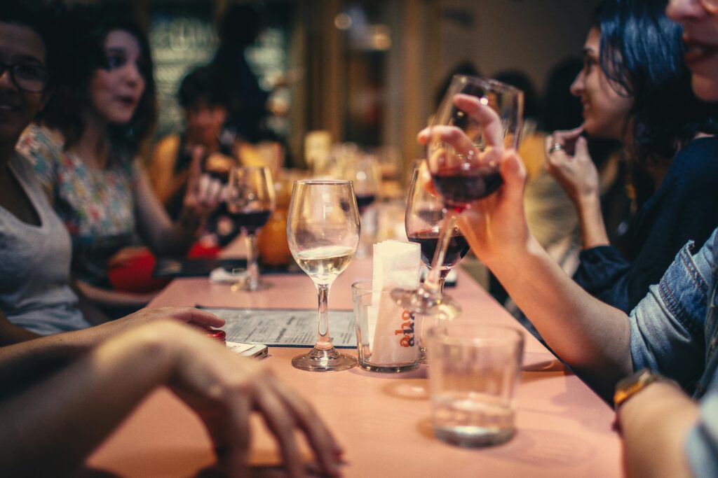 pexels-photo-696218-696218 A lively scene of friends enjoying wine and conversation in a cozy bar setting.